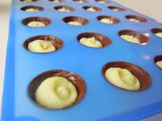 chocolate covered doughnuts are lined up on a blue plastic tray, ready to be baked