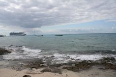 there is a large cruise ship in the distance on the water and rocks at the beach