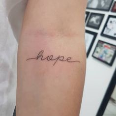 a woman's arm with the word hope written in cursive font on it