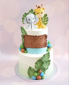 a three tiered cake with an elephant and giraffe on top