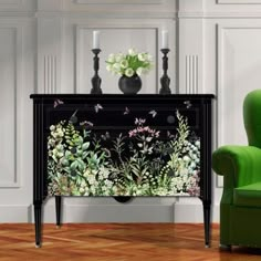 a green chair sitting next to a black cabinet with flowers on it