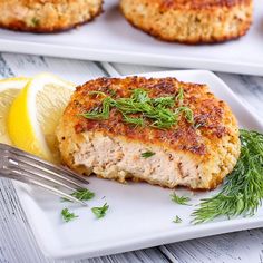 some food is on a white plate with lemon wedges and a fork next to it