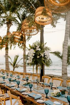 a long table set up with blue and white place settings for an ocean themed dinner