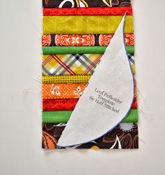 a stack of multicolored fabric with a white sailboat on it's side