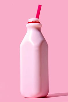 a pink bottle with a straw sticking out of it's top on a pink background