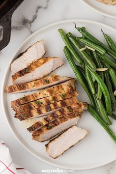 some green beans and chicken on a white plate next to another plate with other food