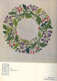 a cross stitch wreath with flowers and leaves