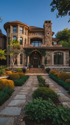 a large stone house with lots of plants and trees around it's front entrance