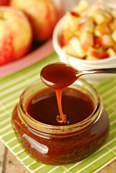 a spoon full of caramel sauce next to some apples