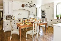 a kitchen with white cabinets and an island in the middle, surrounded by wooden flooring