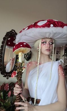 a woman with white hair wearing a mushroom hat and holding a lamp in her hands