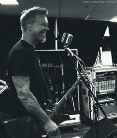 a man standing in front of a microphone next to a recording equipment set up behind him