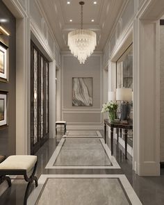 an elegant hallway with chandelier and art work on the walls, carpeted flooring