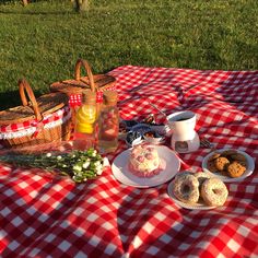 a picnic table with food and drinks on it in the grass, including donuts