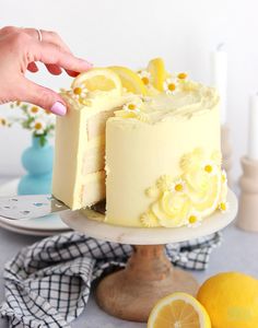 someone is cutting into a cake with lemons on the side