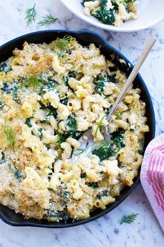 a skillet filled with macaroni and cheese on top of a marble counter