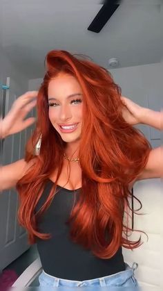 a woman with long red hair is posing for the camera