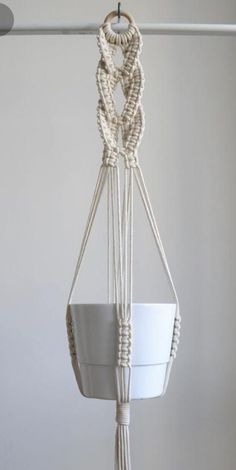 a white pot hanging from a rope in a room