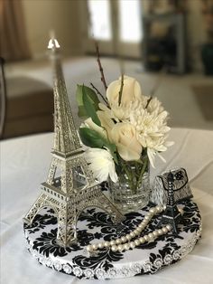 a vase with flowers in it sitting on a table next to the eiffel tower