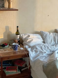 a bottle of wine is sitting on a table next to a bed