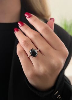 a woman's hand wearing a ring with an oval black stone