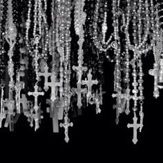 many beads are hanging from the ceiling in this black and white photo with crosses on them