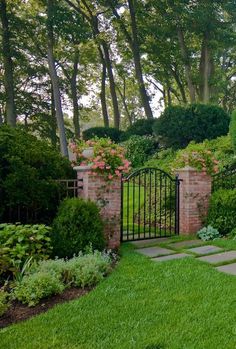 a stone path leading to a gate in the middle of a lush green yard