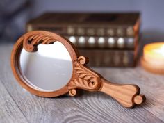 a mirror sitting on top of a wooden table next to a candle and bookcase