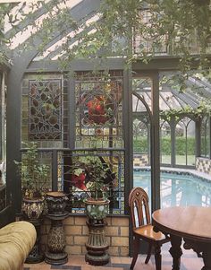 the inside of a house with a pool and glass windows on the wall, surrounded by potted plants