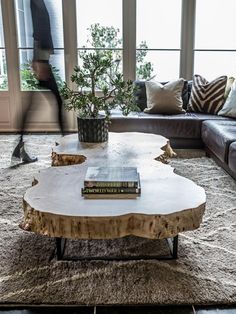 a living room with couches and a table in front of large windows that look out onto the street