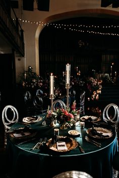 the table is set with plates, silverware and candles for an elegant dinner party