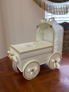 a baby carriage made out of paper on top of a wooden floor next to a window