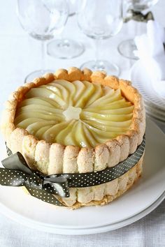 an apple tart on a plate with wine glasses in the background