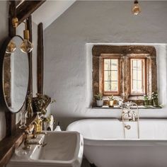 an old fashioned bathtub and sink in a white bathroom with exposed wood beams on the ceiling