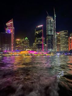 the city skyline is lit up at night with bright lights on it's skyscrapers