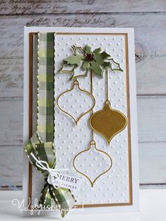 a christmas card with ornaments on it and a ribbon around the edge, sitting on top of a table