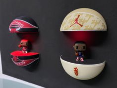 three basketballs are hanging on the wall next to each other with small figurines