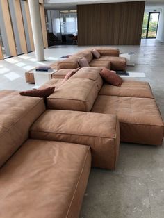 a large sectional couch sitting in the middle of a living room next to an open floor plan