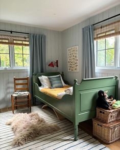 a child's bedroom with striped rug and green bedding, wooden furniture and windows