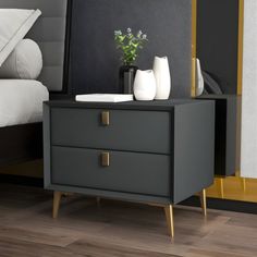 a nightstand with two vases sitting on top of it next to a white bed