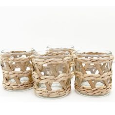 four wicker baskets are lined up on a white surface, with one empty glass in the middle