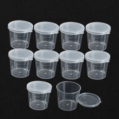 twelve clear plastic cups with lids on black background