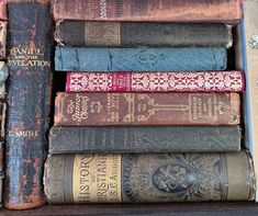 a stack of old books sitting on top of a wooden shelf next to each other