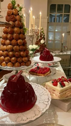 several desserts are displayed on trays with candles in the background, including cakes and pastries