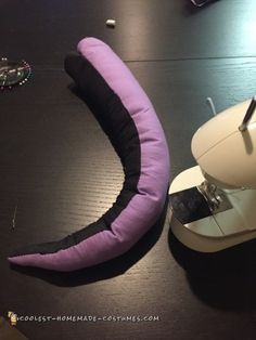 a purple pillow sitting on top of a table next to a sewing machine and scissors