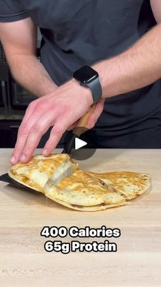 a person cutting up food on top of a wooden table with a knife and fork