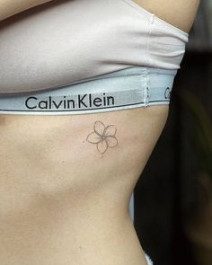 a woman's stomach with a flower tattoo on her left side ribcage