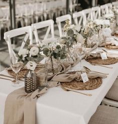 the table is set with white linens and place settings for guests to sit at