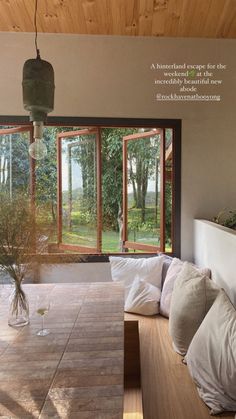 a dining room table and chairs in front of large windows with trees outside the window