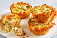 four mini quiches on a white plate with one cut in half to show the filling